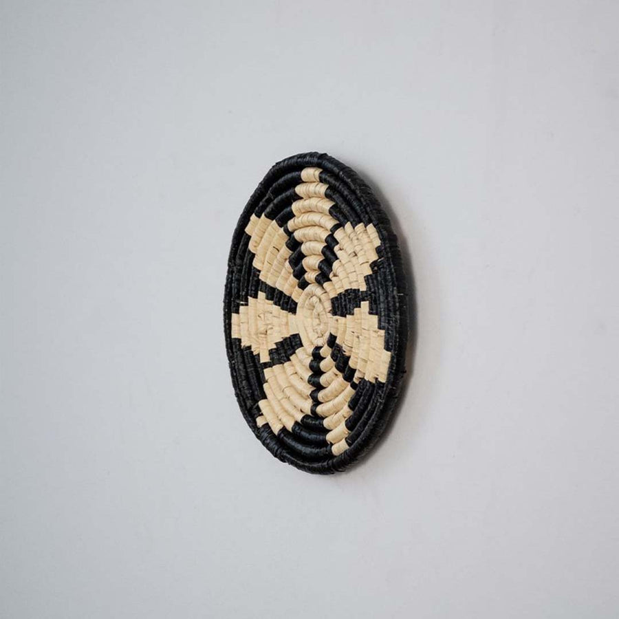Side profile of handwoven bamboo wall plate in black beige tones highlighting crafted weave and natural texture.