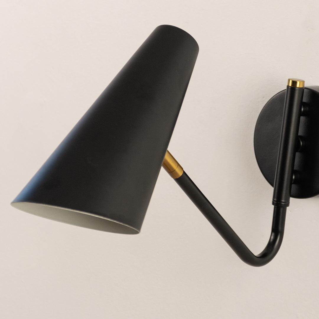 Closeup of black metal wall light with cone shade for modern bedroom hallway and minimalist decor styling spaces.
