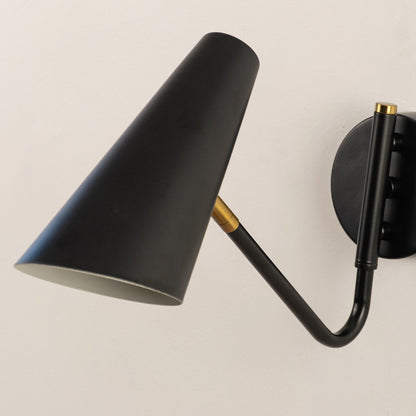 Closeup of black metal wall light with cone shade for modern bedroom hallway and minimalist decor styling spaces.