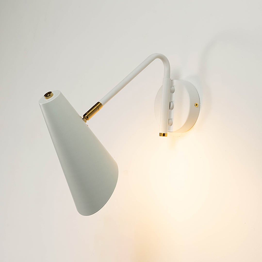 White cone wall light with brass detailing glowing softly against white wall adding refined charm and modern elegance.