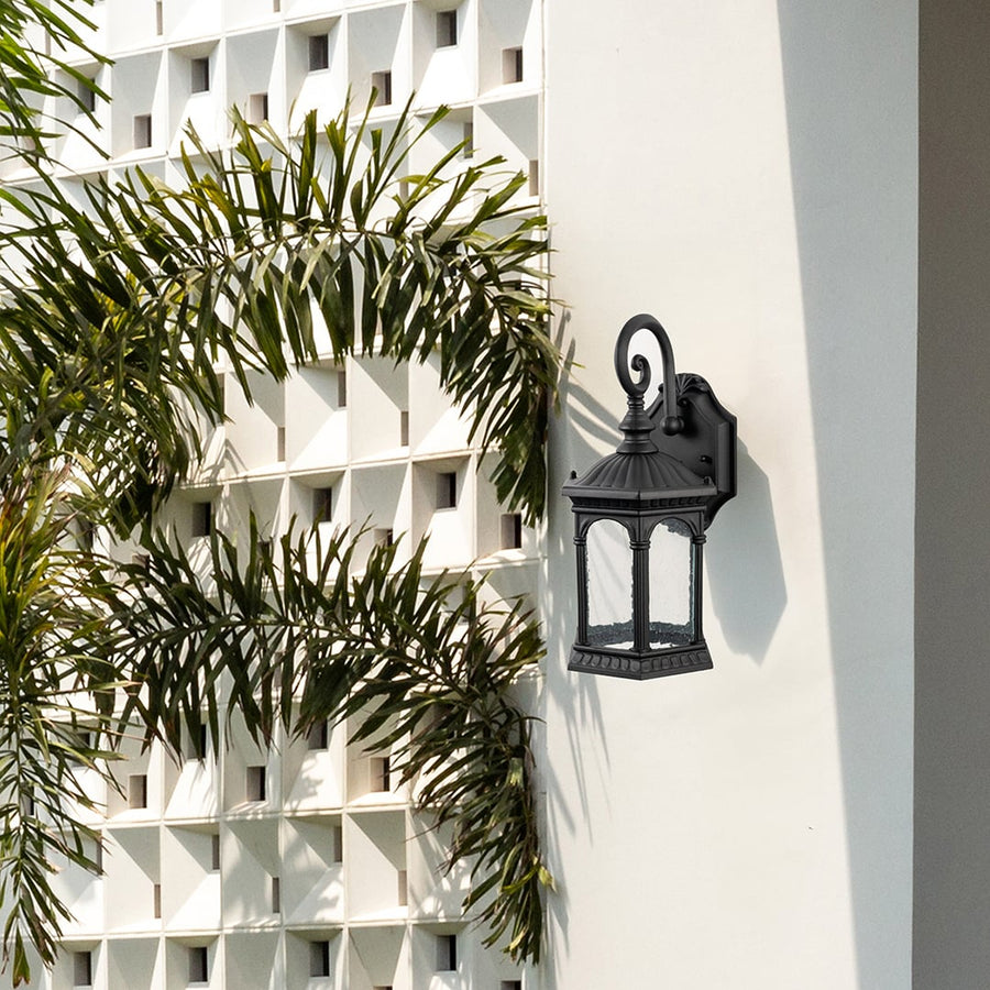 Outdoor wall sconce enhancing home exterior mounted on stone wall near wooden entrance door adding vintage charm.