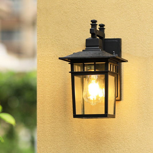 Outdoor wall lantern light illuminating entrance with elegant black frame design for modern exterior decor.