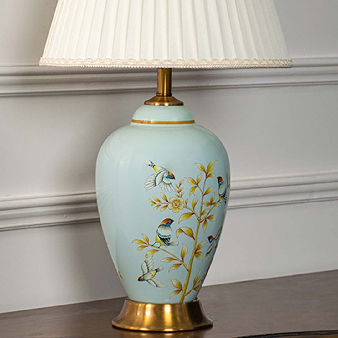 Light blue floral ceramic table lamp showcasing delicate hand painted craftsmanship with brass base and elegant fabric shade.