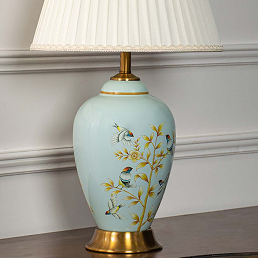 Light blue floral ceramic table lamp showcasing delicate hand painted craftsmanship with brass base and elegant fabric shade.