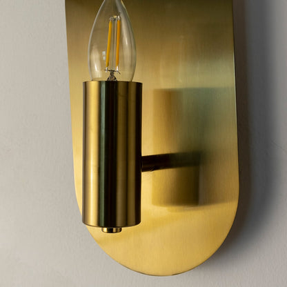 Closeup of modern gold wall sconce showing sleek brushed finish and cylindrical bulb holder for elegant interiors.
