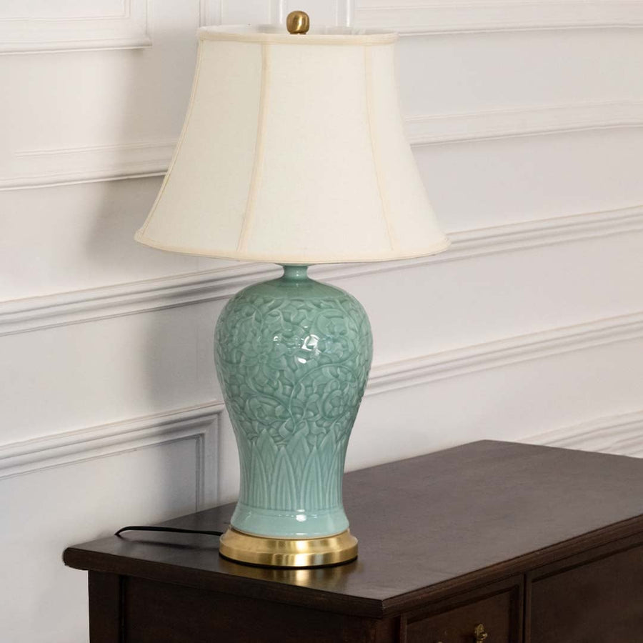 Unlit blue ceramic lamp with gold base and white shade showcases its refined silhouette and exquisite craftsmanship adding artistic charm.