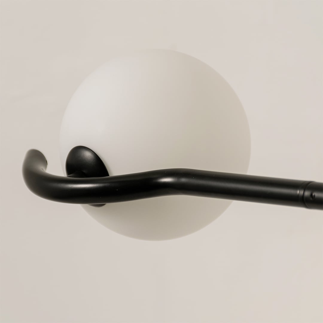 Detailed closeup of black chandelier highlighting sculpted arms and smooth white globes for contemporary home lighting decor.