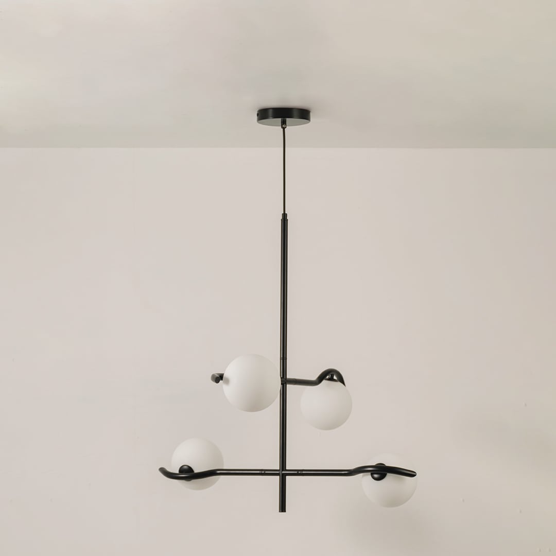 Black metal chandelier with white globes shown on a bright white background with lights off for a sleek minimal modern look.