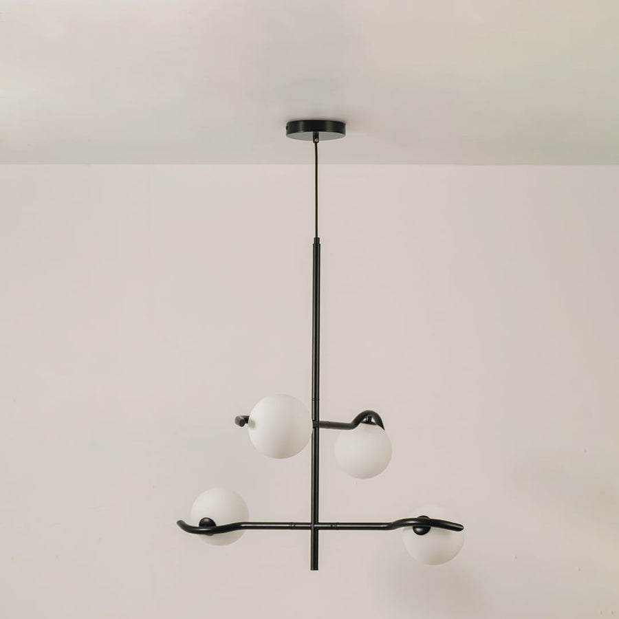 Black metal chandelier with white globes shown on a bright white background with lights off for a sleek minimal modern look.