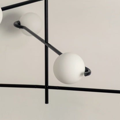 Closeup of black metal chandelier showing curved arms and matte white globes for stylish contemporary interior lighting.