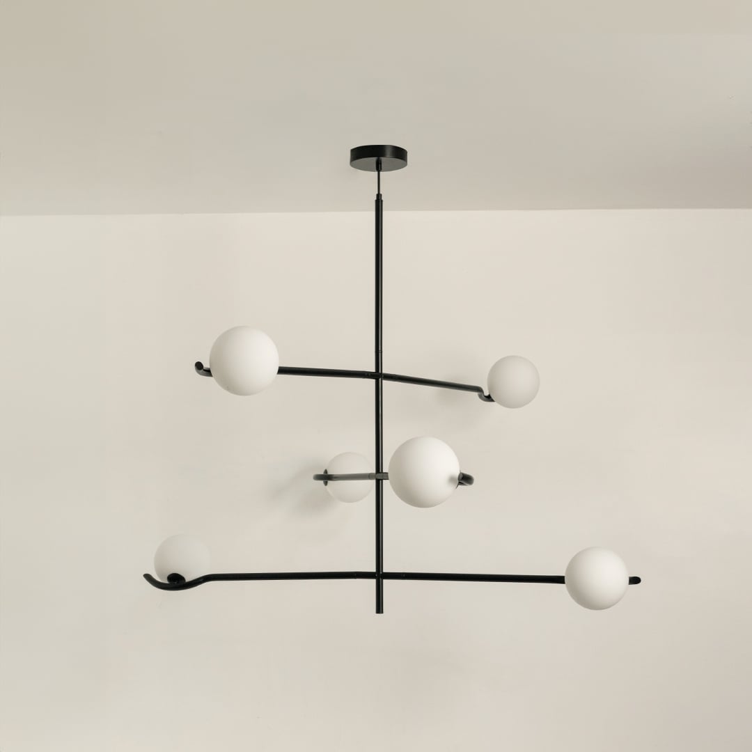 Black metal chandelier with white globes shown on a bright white background with lights turned off for a minimal modern look.