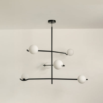 Black metal chandelier with white globes shown on a bright white background with lights turned off for a minimal modern look.
