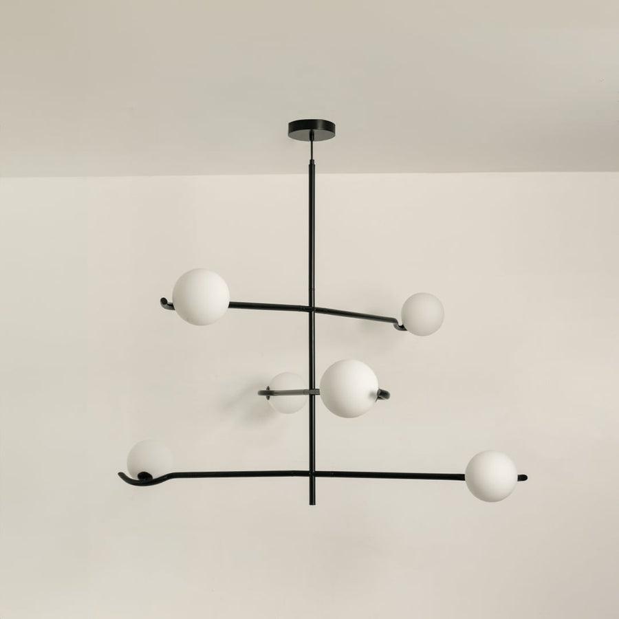 Black metal chandelier with white globes shown on a bright white background with lights turned off for a minimal modern look.