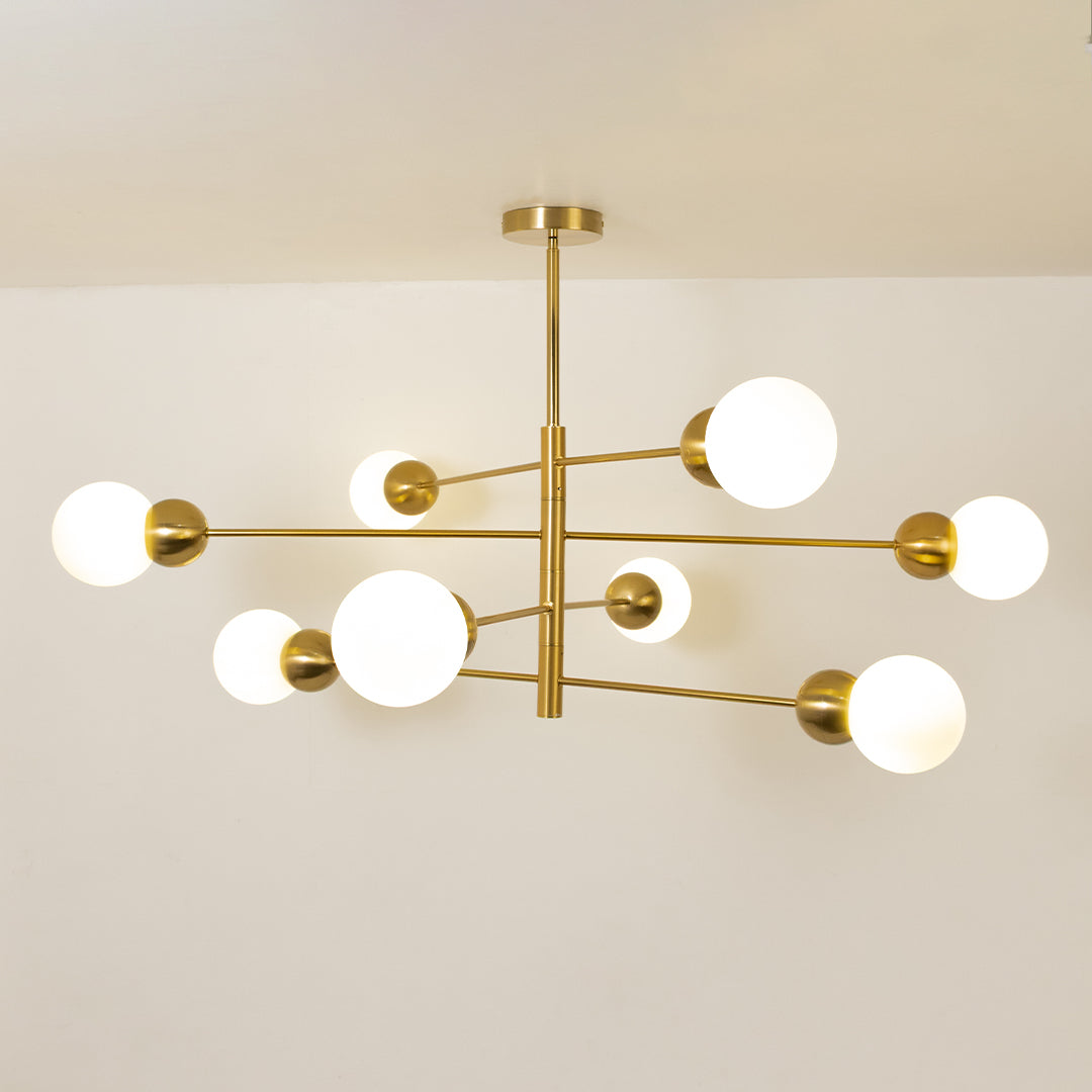 Gold metal chandelier with frosted glass globe shades creating elegant ambient lighting for contemporary interior spaces.
