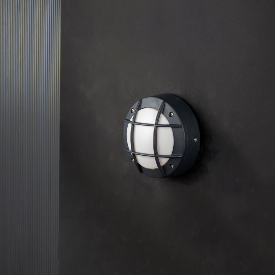 Black metal outdoor wall light with frosted dome shade shown turned off on white background for modern exterior decor.