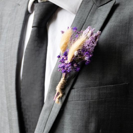 Handmade dried flower boutonniere with preserved purple blooms cream stalks and jute wrap perfect for groom wedding accessory.