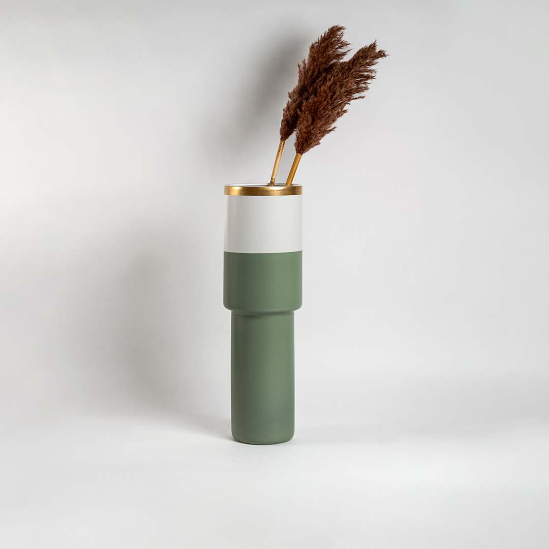 Tall sage green ceramic vase with gold rim and white band placed in a bright interior perfect for modern living room and console styling.