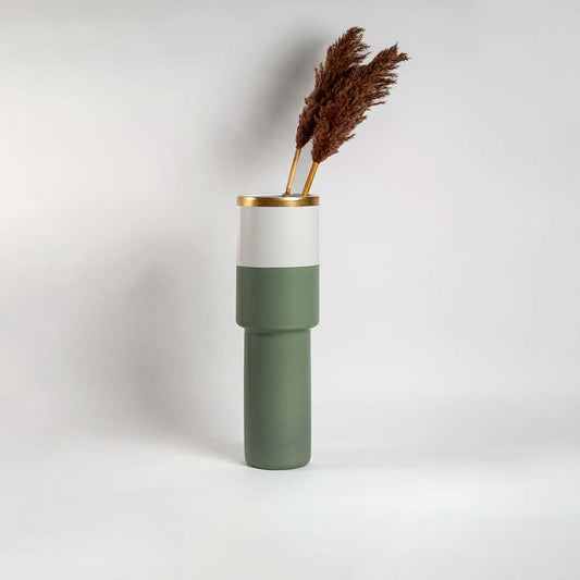 Tall sage green ceramic vase with gold rim and white band placed in a bright interior perfect for modern living room and console styling.