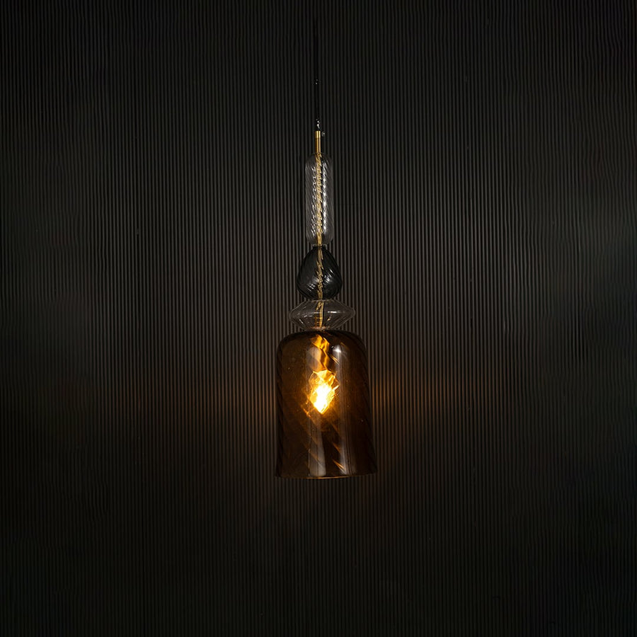 Elegant gold pendant light illuminated beautifully against dark background highlighting its glossy artistic texture.