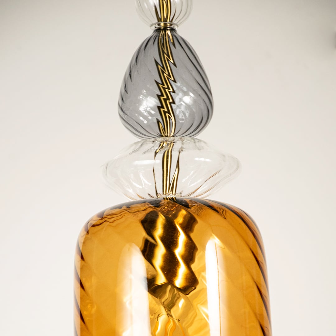 Close view of gold glass pendant light showing textured metallic finish and intricate transparent glass detailing.