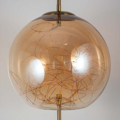 Amber glass globe pendant ceiling light with golden details shown stylishly against black background for modern home decor