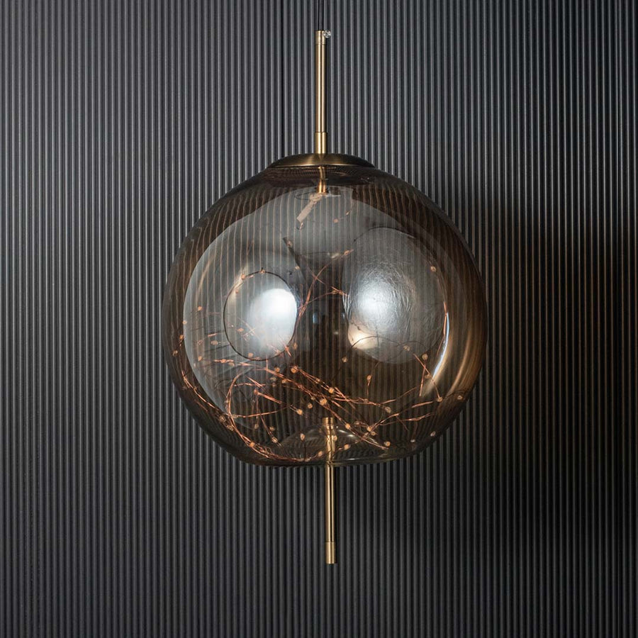 Amber glass globe pendant ceiling light with golden details shown stylishly against black background for modern home decor