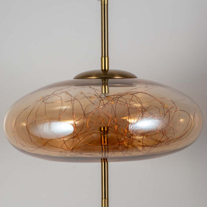 Closeup of amber glass pendant light with artistic wire detailing showcasing luxurious craftsmanship.
