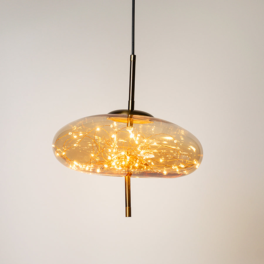 Decorative glass pendant light with warm glowing bubble texture and hanging cord placed against neutral wall background creating ambient modern lighting appeal.