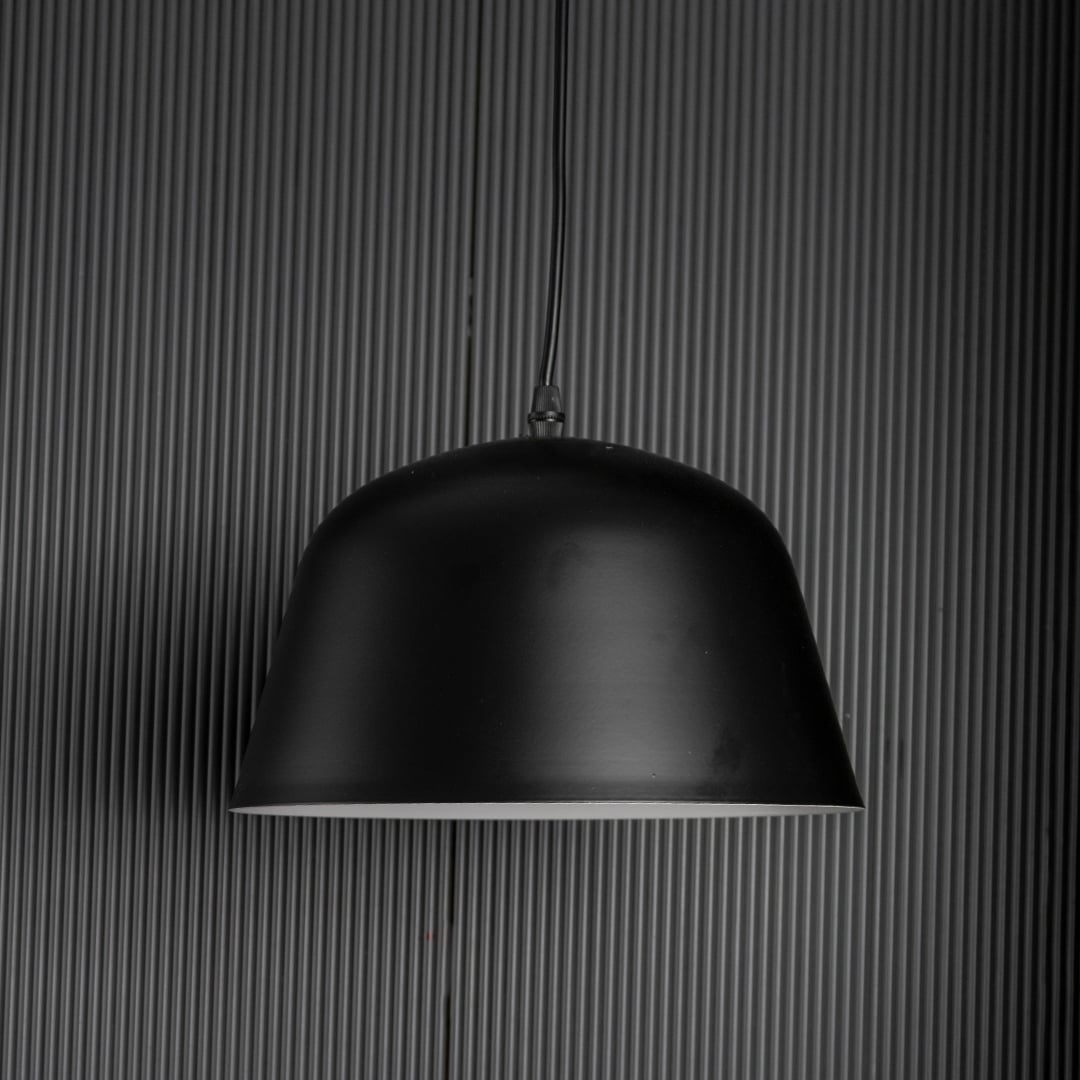 Matte black dome pendant light turned off against dark backdrop emphasizing its sleek silhouette and modern texture.