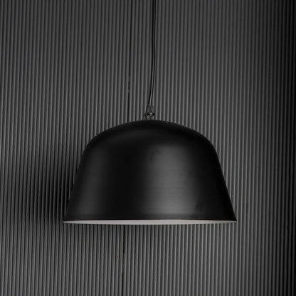 Matte black dome pendant light turned off against dark backdrop emphasizing its sleek silhouette and modern texture.