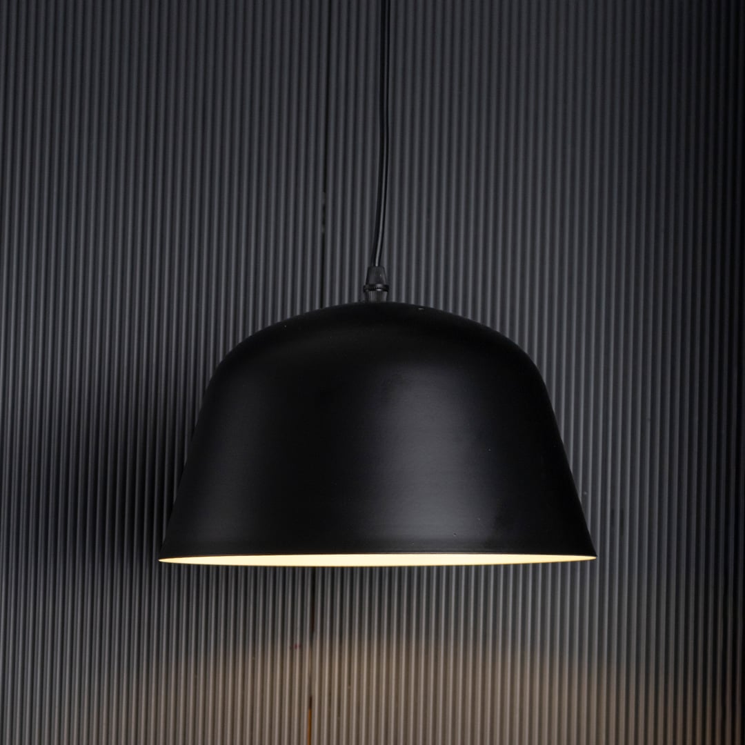 Matte black dome pendant light on black background showing smooth curved shade and refined matte finish.
