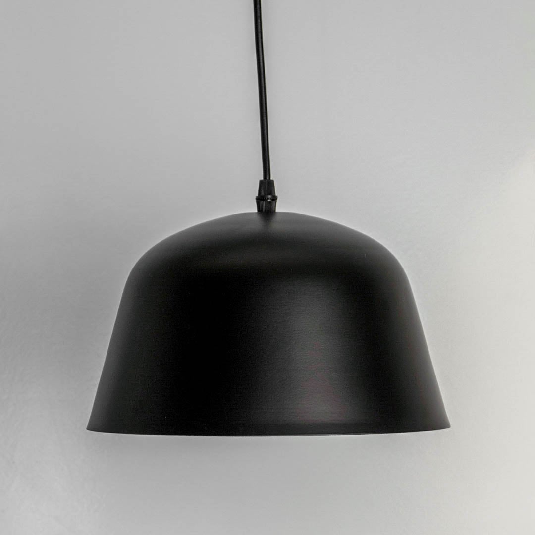 Matte black dome pendant light turned off against white backdrop emphasizing its sleek silhouette and modern texture.