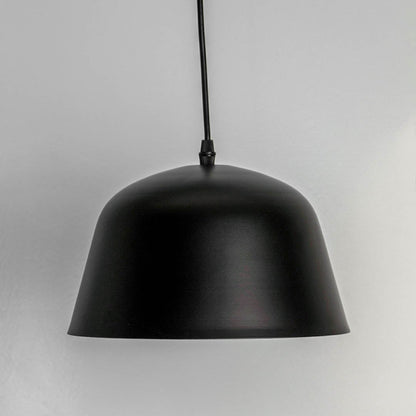 Matte black dome pendant light turned off against white backdrop emphasizing its sleek silhouette and modern texture.