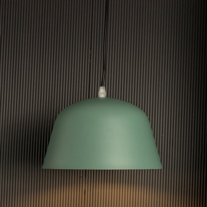 Matte green dome pendant light glowing softly against dark background emphasizing its elegant matte texture and shape.