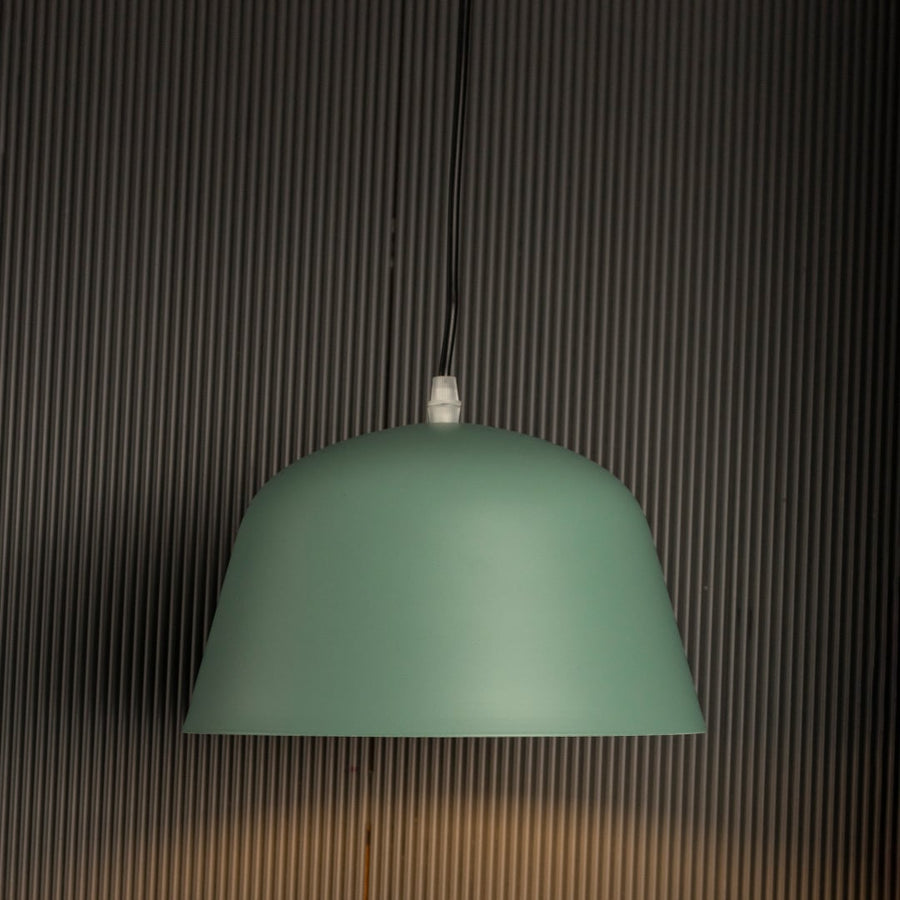 Matte green dome pendant light glowing softly against dark background emphasizing its elegant matte texture and shape.