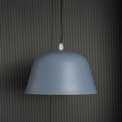 Matte blue dome pendant light turned off against dark ribbed background highlighting its smooth surface and clean form.