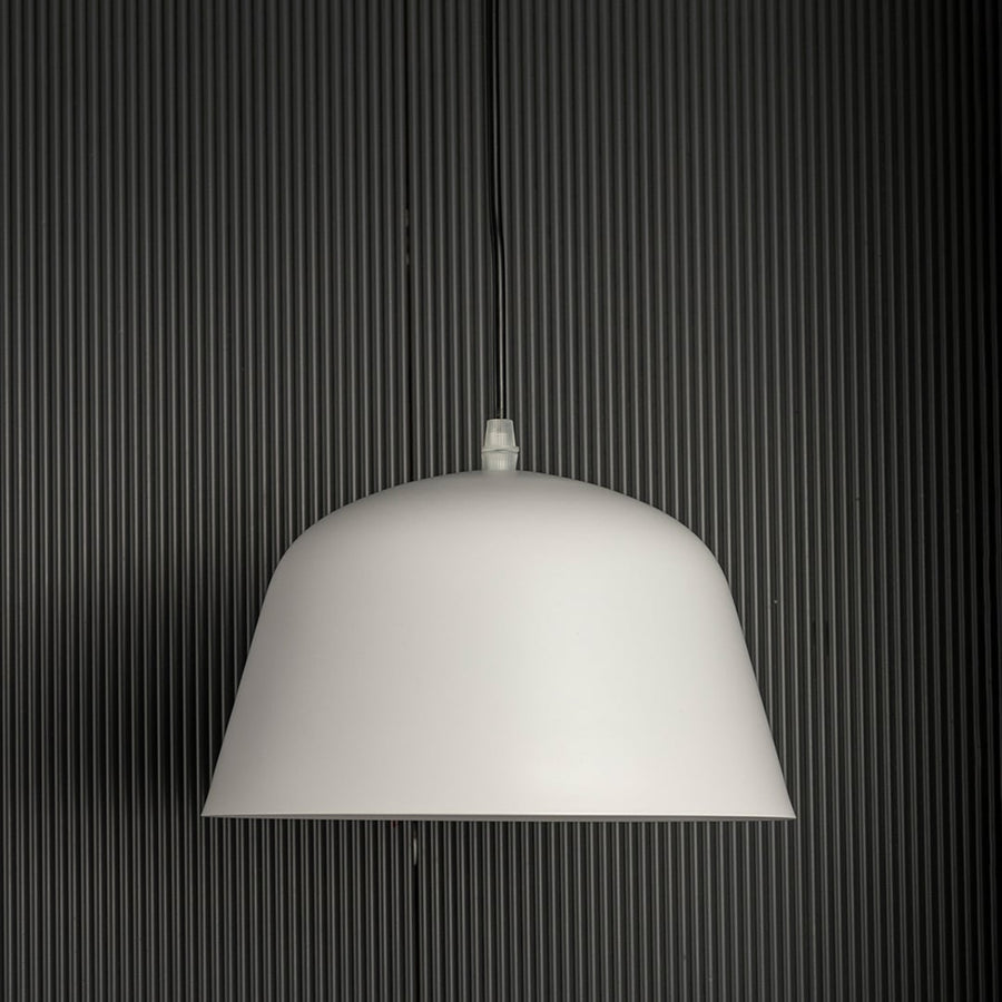 Matte white dome pendant light off gently against a dark background highlighting its smooth modern silhouette.