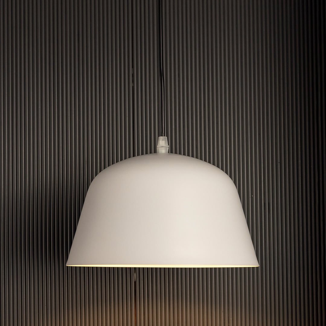 Matte white dome pendant lights softly glowing against black background together creating bright elegant lighting in modern interiors.