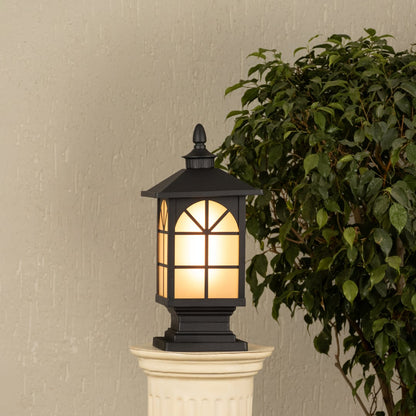 Black outdoor gate light with warm glowing panels styled beside plants for elegant exterior decor ambiance.