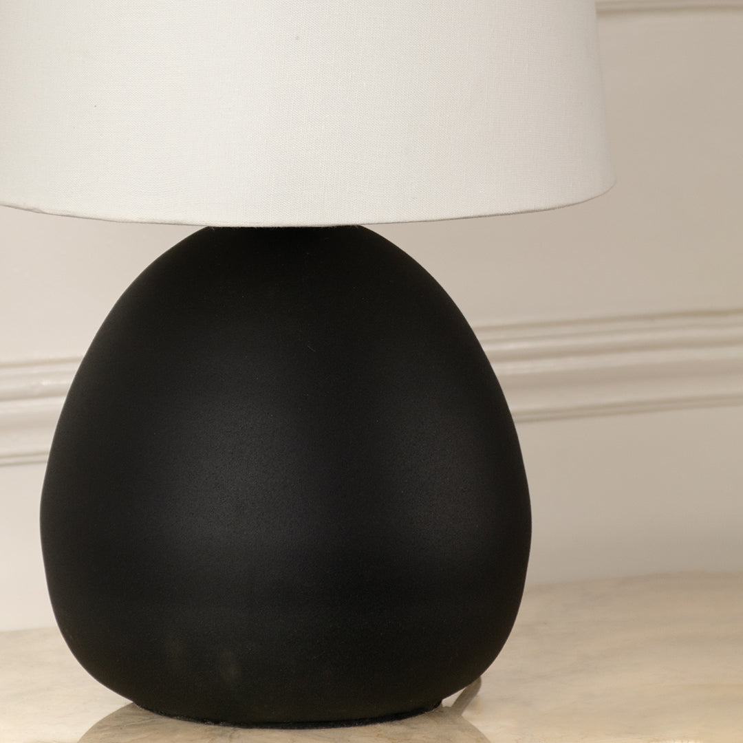 Closeup of black metal table lamp base with smooth rounded shape highlighting modern minimal design for interior decor styling.