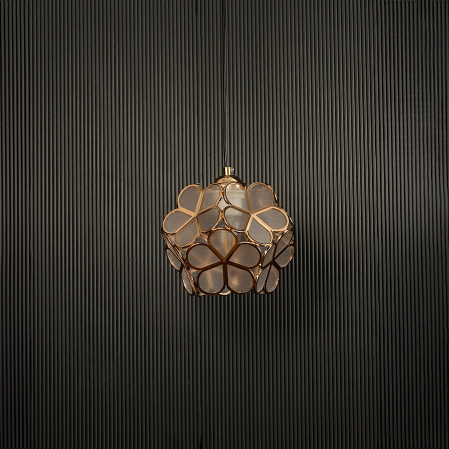 Modern gold flower pendant light displayed on dark background with light off highlighting elegant design details.