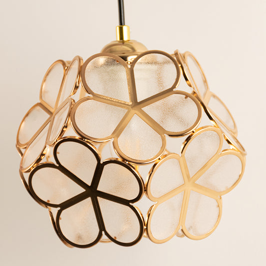 Closeup of floral white glass and gold metal pendant light for luxury bedroom and elegant decor styling spaces.
