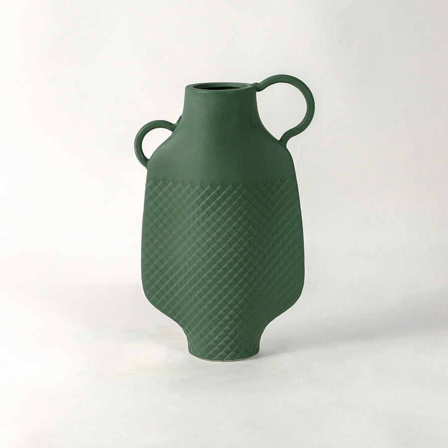 Green ceramic vase with dual side handles and textured surface placed on white surface against neutral background enhancing contemporary home decor aesthetic.