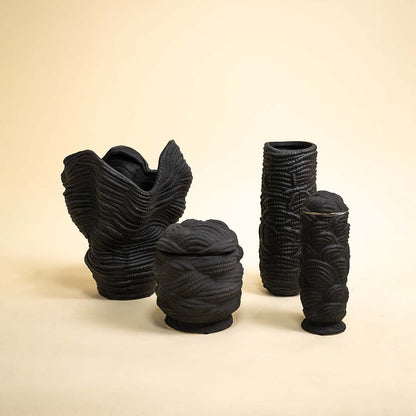 Set of handcrafted black textured ceramic vases arranged together near natural light showcasing unique modern and sculptural home accents.