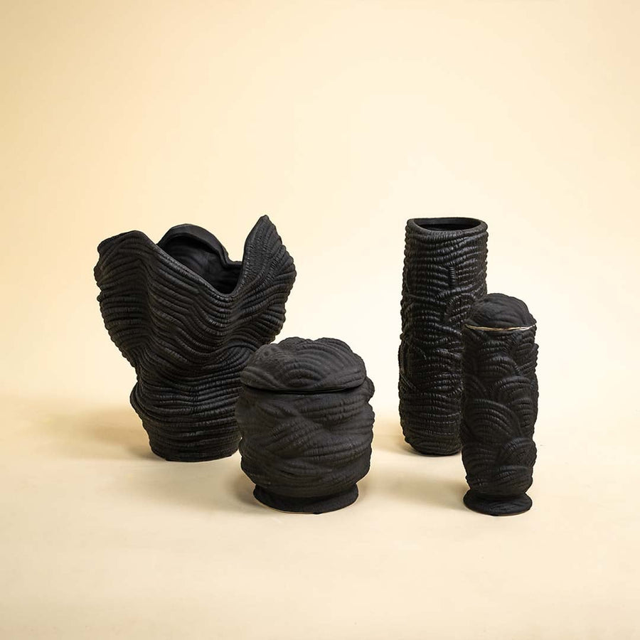 Set of handcrafted black textured ceramic vases arranged together near natural light showcasing unique modern and sculptural home accents.