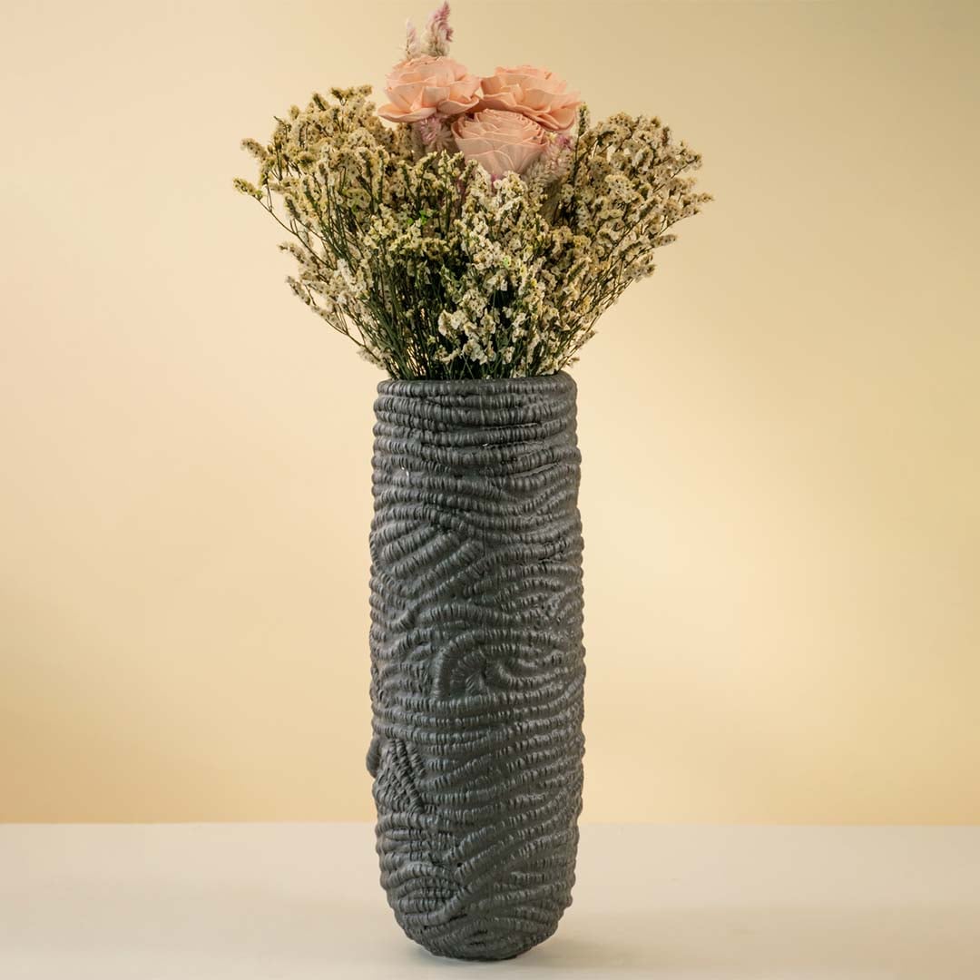 Tall black textured ceramic vase styled with pink and white dried flowers placed on a neutral background adding elegance to modern home decor.