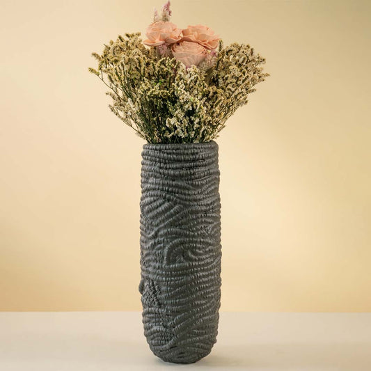 Tall black textured ceramic vase styled with pink and white dried flowers placed on a neutral background adding elegance to modern home decor.