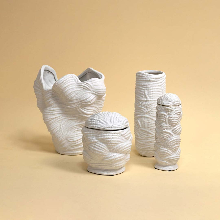 Set of white ceramic vases with similar textured design arranged together creating a cohesive and elegant modern decor look.