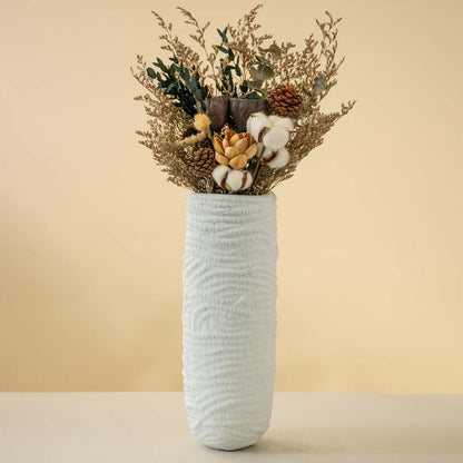 Elegant white ceramic vase with artistic textured detailing softly illuminated on a white background showcasing its handcrafted charm.