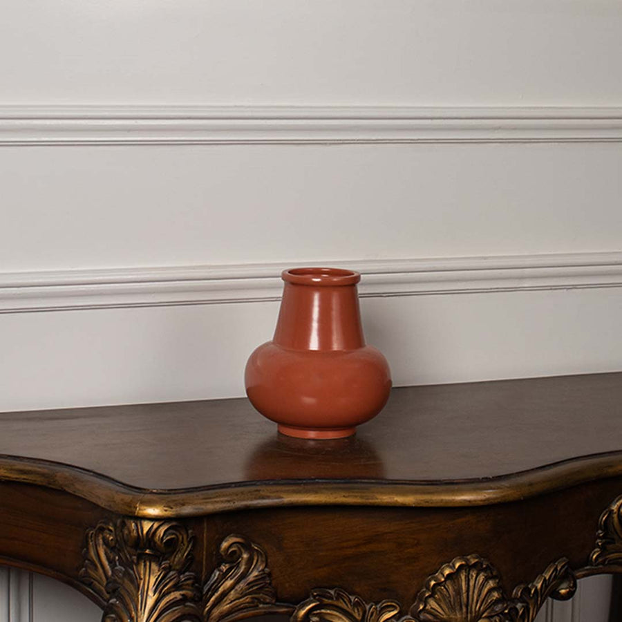 Minimal white background view of the orange ceramic vase showcasing its glossy surface and contemporary rounded design.